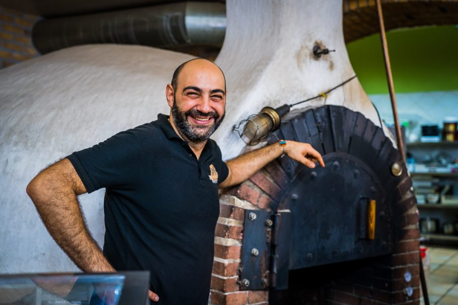Greek cafe owner standing next to oven